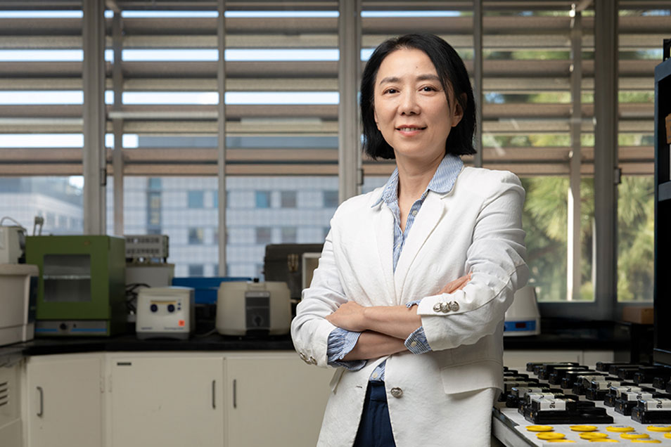 Air-quality researcher Yifang Zhu wearing a white coat stands in a lab setting